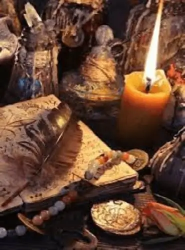 Imagen que representa el servicio de Lecturas Personalizadas de Energía, con un libro místico, pluma de escritura, amuletos, collares, vela encendida, flores y una llave, elementos que simbolizan nuestros Rituales Personalizados de Brujería