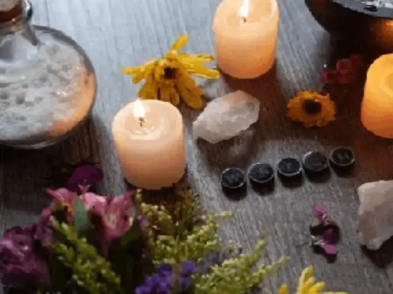 Imagen de velas encendidas, flores, un frasco, runas y piedras semipreciosas, simbolizando las respuestas del universo y nuestros Servicios de Magia Personalizada. Contáctanos!.