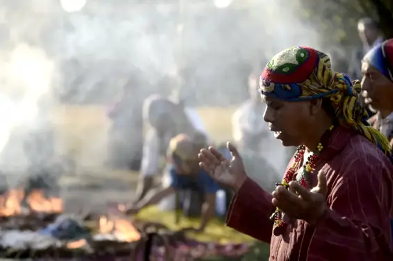 Persona de rodillas en la tierra, orando con profunda devoción, representando un ritual de Invocaciones Místicas.
