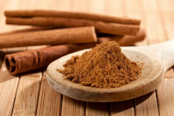 Cuchara con polvo de canela y rollos de canela, ingredientes esenciales en el baño de pies purificador para atraer abundancia y limpiar energías.