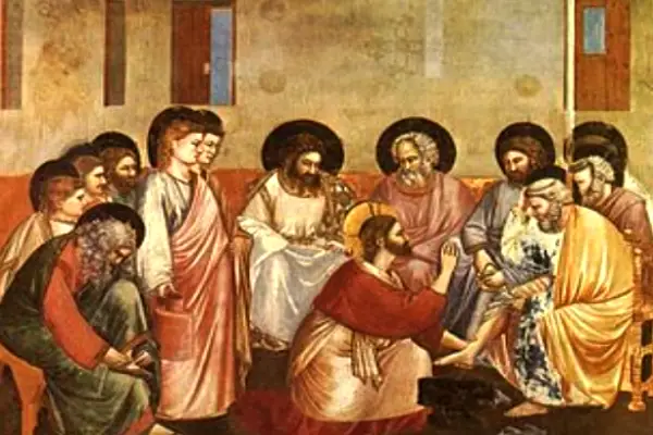 Jesús lavando los pies de uno de sus discípulos, simbolizando humildad, purificación y servicio en el ritual del baño de pies purificador.