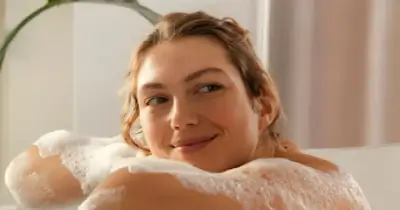 Mujer sonriendo mientras toma un baño relajante para una limpieza profunda del aura.