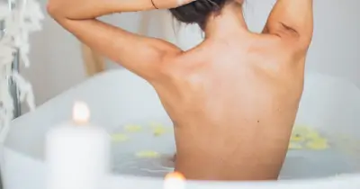 Mujer en la tina preparándose para un baño de limpieza profunda del aura.