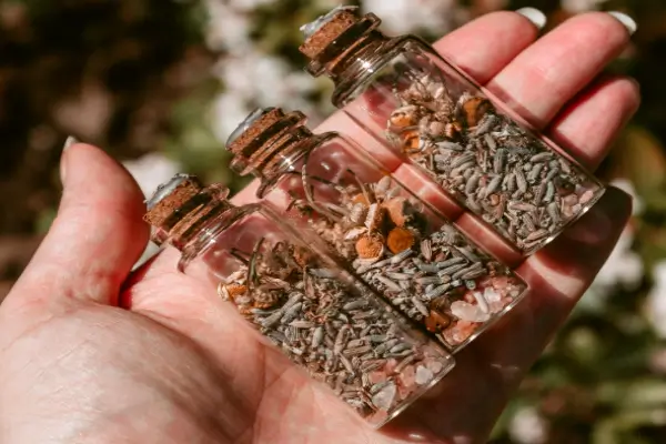 Mano con frascos de vidrio con semillas usadas en hechicería digital.