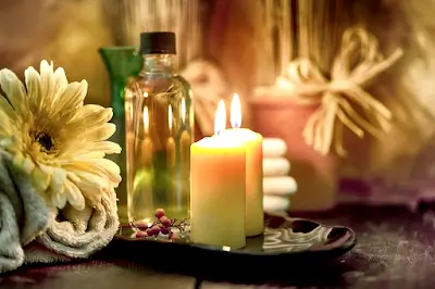 Esencia, velas encendidas y flores alrededor de un cuenco ceremonial para un baño mágico de luz.