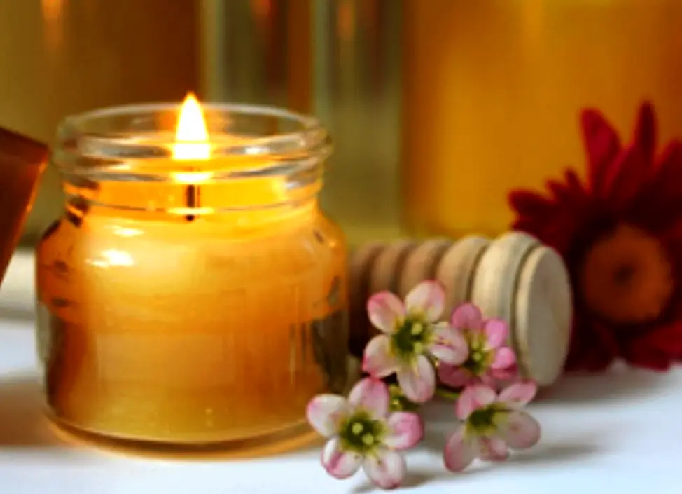 Baño Mágico de Luz ✨ Ritual para Iluminar tu Esencia 1 Vela en frasco encendida junto a flores para un baño mágico de luz.