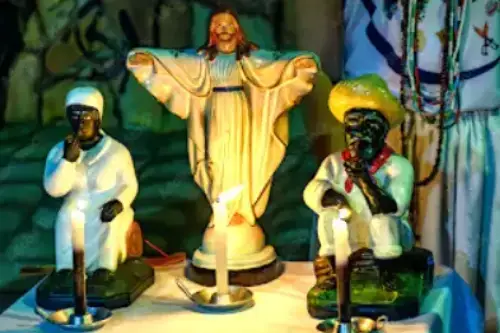 Orígenes de la Macumba. Altar con tres estatuillas y tres velas encendidas.