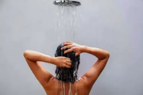 Mujer bajo la ducha realizando un baño de descarga espiritual para purificación y energía positiva
