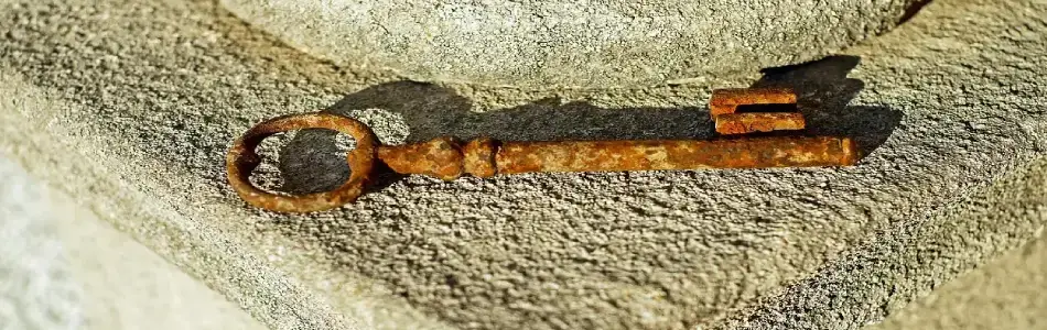 Primer plano de una llave antigua y oxidada descansando bajo la luz directa del sol sobre una superficie rústica, simbolizando el proceso de limpieza de caminos y el despertar tras la inercia.