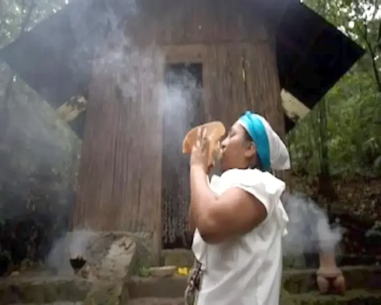 Primer plano de una mujer mayor con rasgos de sabiduría (Abuela Medicina) realizando un ritual de sahumado con incienso para la protección de energía vital y limpieza de negatividad.