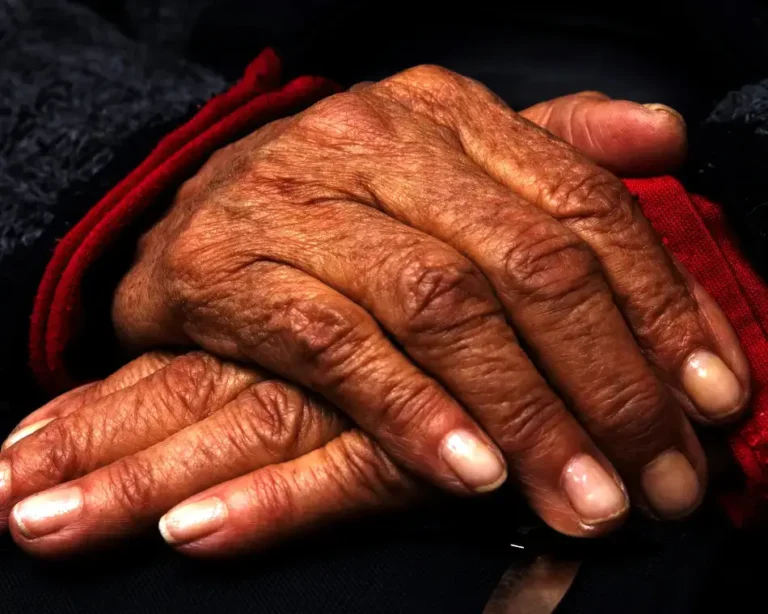 Primer plano detallado de las manos arrugadas de un anciano en reposo, simbolizando la sabiduría acumulada y la capacidad de percibir las señales de que el universo te responde.