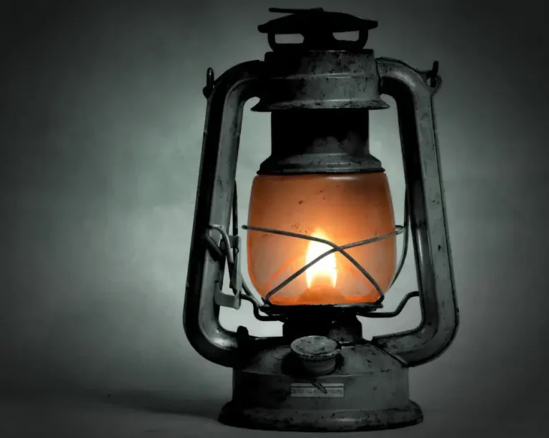Farol antiguo de metal con la mecha encendida emitiendo luz cálida en la oscuridad, representando la guía en el exorcismo digital.