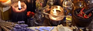 Contáctanos! Mesa de trabajo mística con ramo de lavanda, velas encendidas, piedras semipreciosas, frascos, hierbas y mortero, reflejando la esencia de Bruja Antigua Mayor.